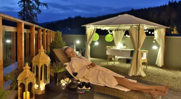 Relaks na tarasie, idealne miejsce gdzie na babski weekend. Kobieta w szlafroku odpoczywa przy winie i herbacie.