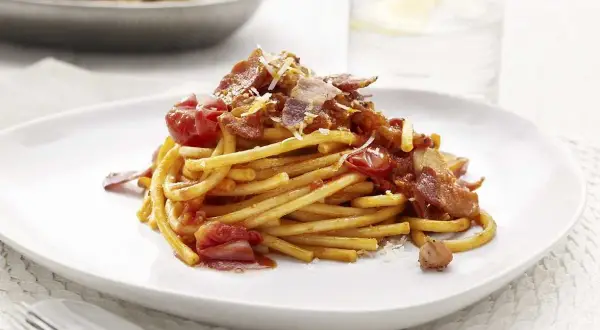 En portion pasta amatriciana med tomatsås, bacon och parmesanost.