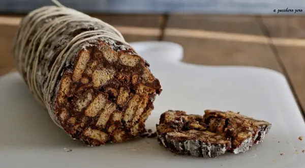 Salame dolce con cacao, un goloso rotolo di biscotti e cioccolato, legato con spago e cosparso di zucchero a velo.