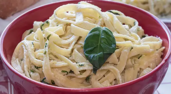 Tagliatelle condite con un delizioso sugo burro e salvia, guarnite con una foglia di basilico fresco.