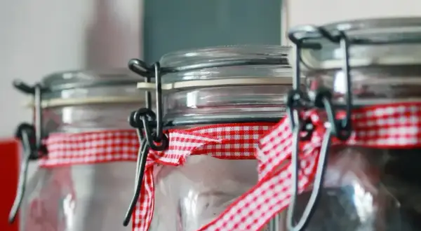 Słoiki z nalewkami, ozdobione czerwoną kratką. Czy nalewka może sfermentować? Zależy od składników i sposobu przygotowania.