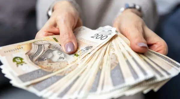 Dłonie trzymają wachlarz banknotów 200 zł. Zastanawiasz się, ile zarabia hotelarz?