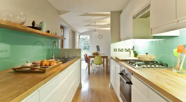 Cocina moderna con encimeras de madera, salpicadero verde menta y electrodomésticos integrados. Ideas para como diseñar una cocina funcional y estilosa.