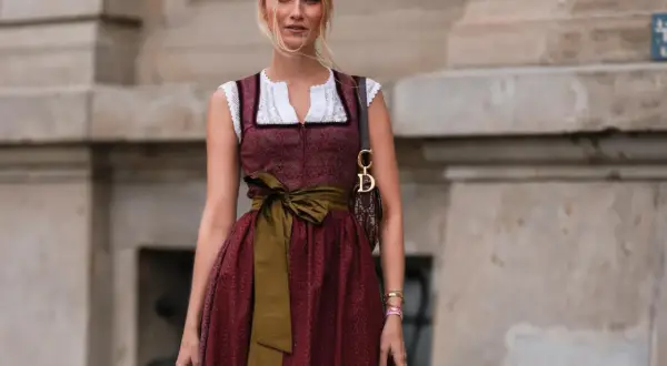 Frau mit Dirndl und einer grünen Schürze, die sie elegant um die Taille gebunden hat.