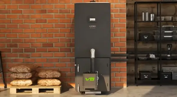 Nowoczesny piec na pellet z zielonym logo, obok palety z pelletem. Dofinansowanie do pieca węglowego może pomóc w zakupie ekologicznego ogrzewania.