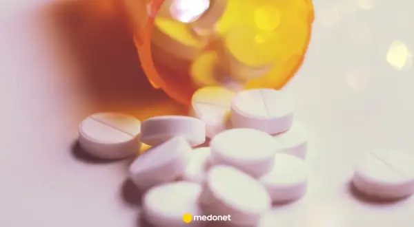 Białe tabletki, w tym lorazepam, wysypują się z pomarańczowego pojemnika.