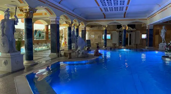 Prunkvoller Innenpool mit blauer Beleuchtung, antiken Statuen und Säulen. Ein Ort der Entspannung in den Teplice Therme.