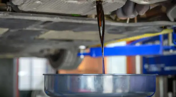 Altöl fließt aus dem Getriebe eines Autos in eine Auffangschale.