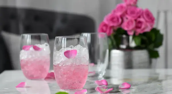 Różowe drinki z winem, lodem i płatkami róż. Eleganckie, orzeźwiające napoje na letnie popołudnie.