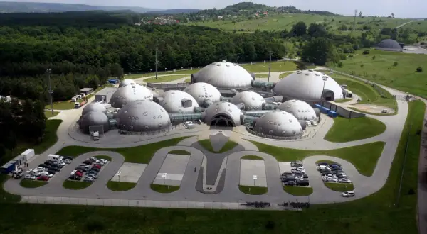Kompleks kopuł przypominający bazę na planecie Alvernia, otoczony zielenią i lasem.