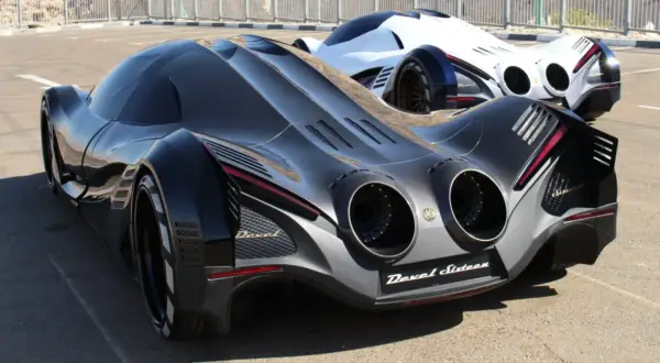 Dwa futurystyczne samochody Devel Sixteen, jeden czarny, drugi biały, stoją na asfalcie.