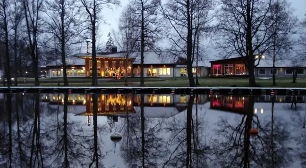 Vinterkväll vid Best Western Norra Vättern. Hotellets ljus speglas i vattnet, omgivet av kala träd.
