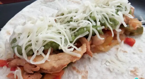 Fajitas de pollo y queso, con guacamole y pimientos salteados, envueltas en tortilla.