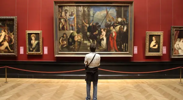 A person contemplates a large painting in a museum, perhaps inspired by the best art history graduate programs.