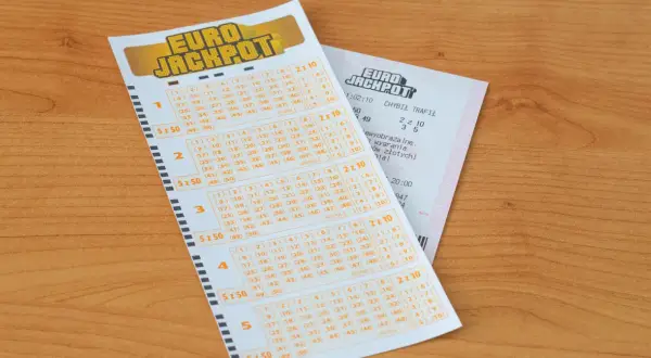 Kupon Eurojackpot na drewnianym blacie. Zastanawiasz się, ile trwa losowanie Eurojackpot? Sprawdź swoje szczęśliwe liczby!