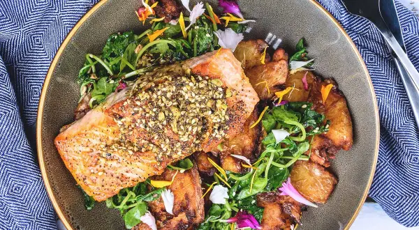 Filet de saumon croustillant, parsemé de graines, servi avec des pommes de terre rôties et une salade verte. Un accompagnement poisson savoureux et coloré.