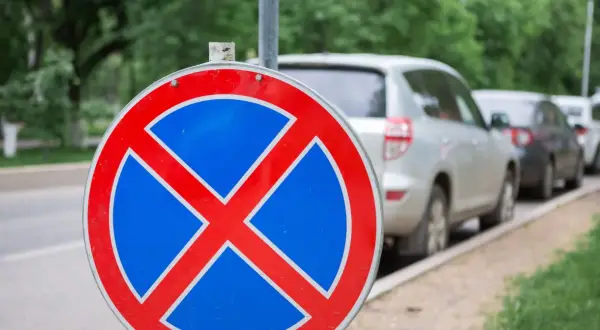 Znak b36 zakazu zatrzymywania się. Samochody stojące w rzędzie na poboczu drogi.