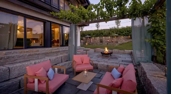 Gemütliche Lounge-Möbel und ein Feuerkorb laden zum Entspannen ein. Die Weinreben über der Pergola und Lichterketten schaffen eine romantische Atmosphäre, perfekt, um die Terrasse zu dekorieren.