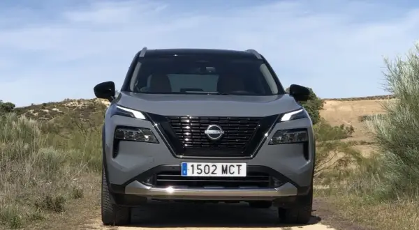 Grå Nissan X-Trail står på en grusväg. En potentiell nissan x-trail problem kan vara att den fastnar i terrängen.