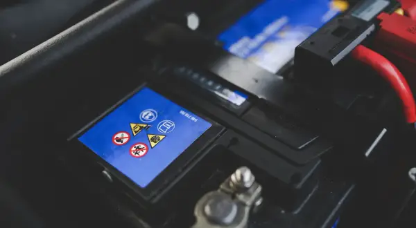 Bilbatteri med varningssymboler. Ett dåligt bilbatteri symptom kan vara att bilen inte startar.