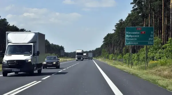 Droga ekspresowa jednojezdniowa S10 wśród lasu. Samochody i ciężarówki jadą w kierunku Nieszawki, Bydgoszczy, Szczecina i Lubieszyna.