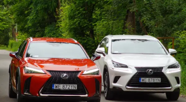 Dwa modele Lexus SUV: czerwony UX i biały NX, zaparkowane na tle zieleni.