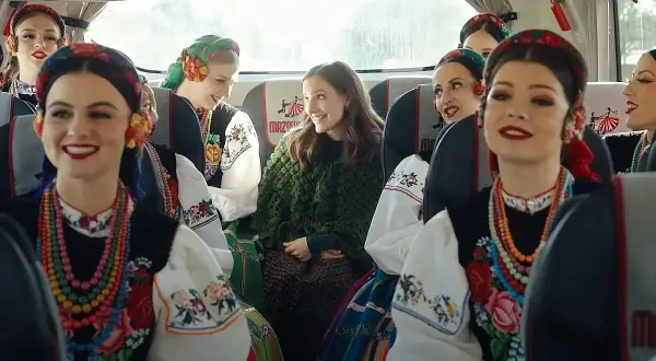 Uśmiechnięte dziewczyny w strojach ludowych, podróżujące autobusem Mazda. Kolorowe korale i haftowane bluzki.