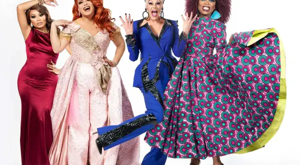 Cztery drag queen w barwnych strojach pozują do zdjęcia na białym tle.