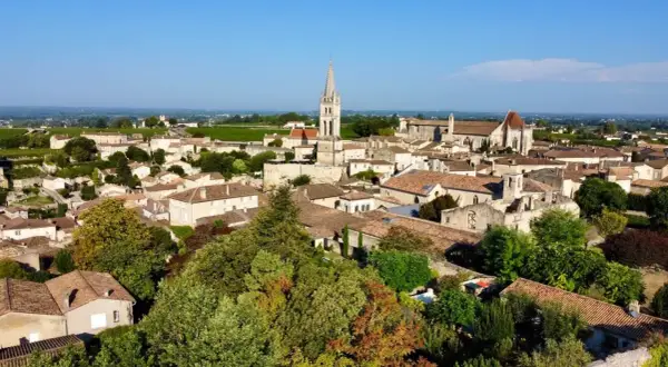 Malowniczy widok na miasteczko Saint-Émilion z charakterystyczną wieżą kościelną i winnicami w tle.