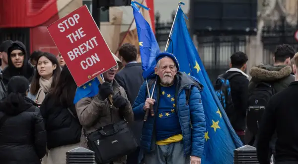 Protestujący w Wielkiej Brytanii z flagami UE i transparentem "Stop the Brexit Con".