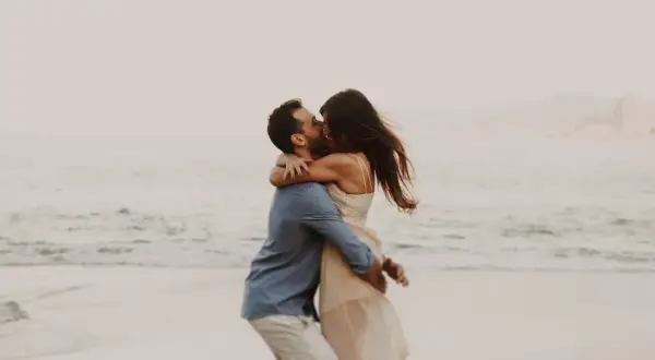 Pareja besándose en la playa, un abrazo que expresa los lenguajes del amor.