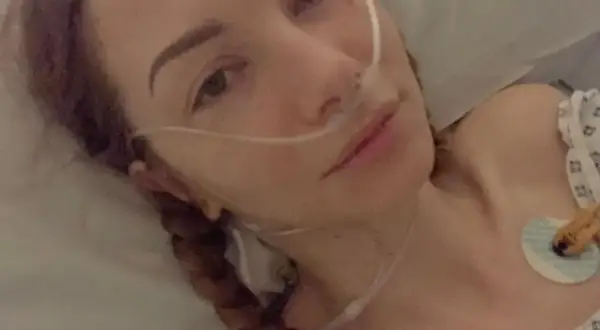 Młoda kobieta z zespołem Ehlersa-Danlosa w szpitalnym łóżku, z rurką tlenową przy nosie. Jej twarz jest blada, a oczy lekko zmęczone.