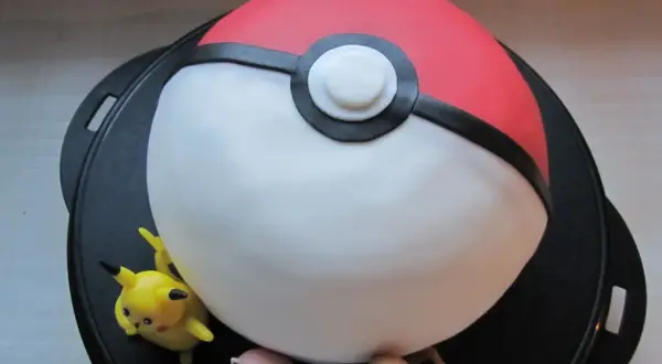 En pokemon tårta formad som en pokéboll med Pikachu, Jigglypuff och Charmander.