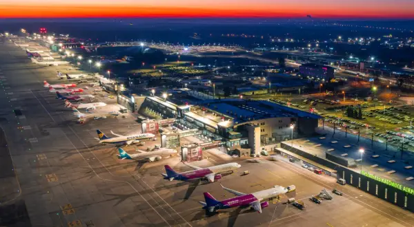 Lotnisko Katowice-Pyrzowice nocą, z samolotami na płycie i oświetlonym terminalem. Rozkład lotów pyrzowice jest dynamiczny.