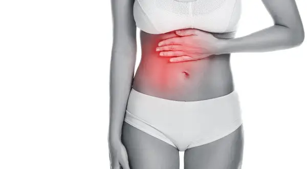 Donna con mano sullo stomaco, evidenziato in rosso. Potrebbe cercare rimedi per il mal di stomaco.