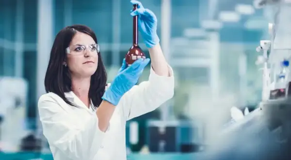 Naukowczyni w laboratorium bada płyn w kolbie. Czy leczenie biologiczne to chemia? Badania naukowe pomagają odpowiedzieć na to pytanie.