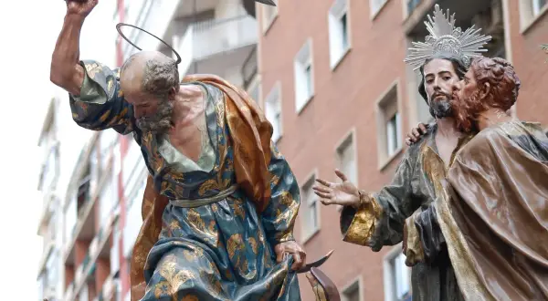 Escena de la **procesión Domingo de Ramos**: un hombre con túnica dorada levanta un sable, mientras otro hombre besa a Jesús.