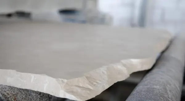 Surowy, jasny wapień na linii produkcyjnej. Kamień o nierównych krawędziach czeka na dalszą obróbkę.