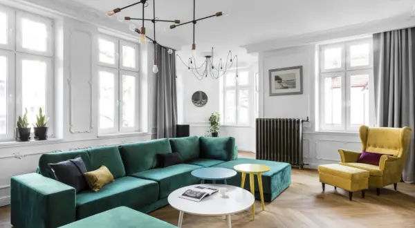 Elegancki salon z butelkową zielenią kanapy, żółtym fotelem i stolikami. Z czym połączyć butelkową zieleń? Zobacz inspiracje.