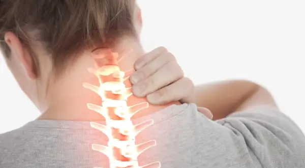 Une personne se tient le cou, montrant une colonne vertébrale cervicale enflammée. La durée de la crise d'arthrose cervicale peut varier.