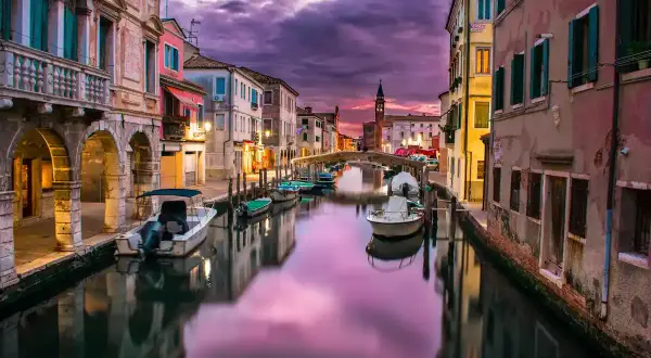 Un canal vénitien au crépuscule, avec des bateaux et des bâtiments colorés. Le ciel violet et rose, reflet de l'eau, illustre parfaitement ce qu'est le HDR.