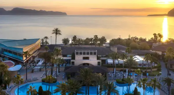 Resortanlage mit Pool und Meerblick bei Sonnenuntergang.