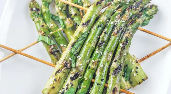 Grillspieße mit Spargel, Sesam und Kräutern auf einem weißen Teller. Perfekt zum Spargel grillen!