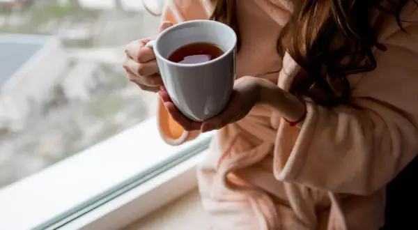 Kobieta w szlafroku trzyma kubek z herbatą. Zastanawiasz się, ile kofeiny ma herbata Earl Grey?