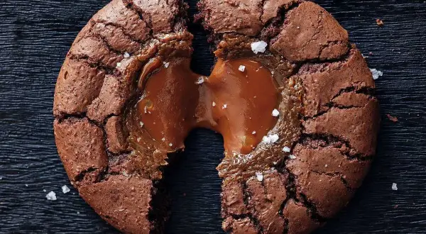 En brownie cookie med flytande karamell som rinner ut, strödd med havssalt.