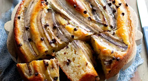 Delizioso dolce con banane mature e gocce di cioccolato, una fetta mostra la morbidezza dell'impasto.