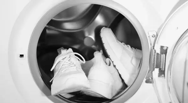 Deux baskets blanches sont prêtes pour leur entretien dans un lave-linge.