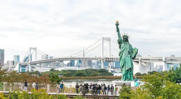 Replika Statuy Wolności w Tokio, gdzie jest statua wolności? W tle most Rainbow Bridge i panorama miasta.