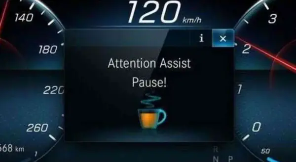 Il display mostra "Attention Assist Pause!" con una tazzina di caffè, indicando come funziona il rilevatore di stanchezza Volkswagen: suggerisce una pausa.
