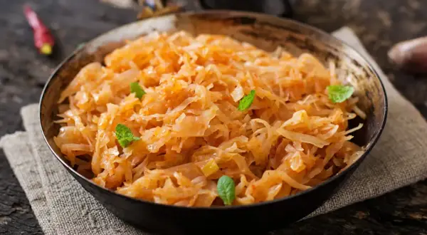 Pyszny bigos wegetariański w misce, ozdobiony listkami mięty. Aromatyczne danie z kapusty i warzyw.